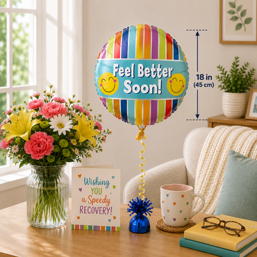 A colorful striped round foil balloon with the words 'Feel Better Soon!' and smiley faces, shown in a styled living room setting next to a bouquet of flowers, a greeting card, a mug, and books. A dimension marker on the right indicates the balloon is 18 in (45 cm) tall.