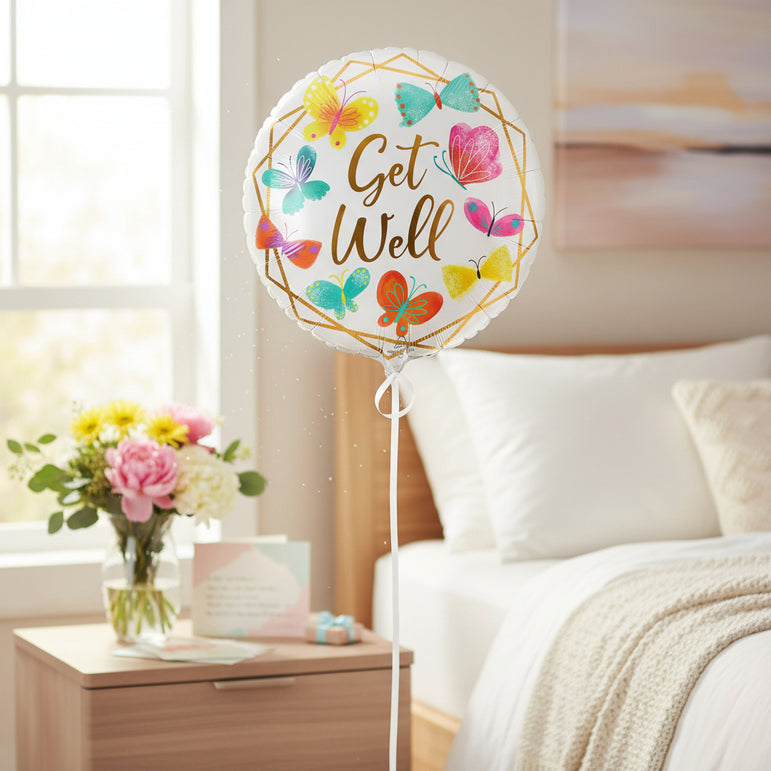 A round white foil balloon with scalloped edges, featuring the phrase 'Get Well' in gold script inside a gold geometric border, surrounded by colorful illustrated butterflies in yellow, teal, pink, orange, and purple on a white background.