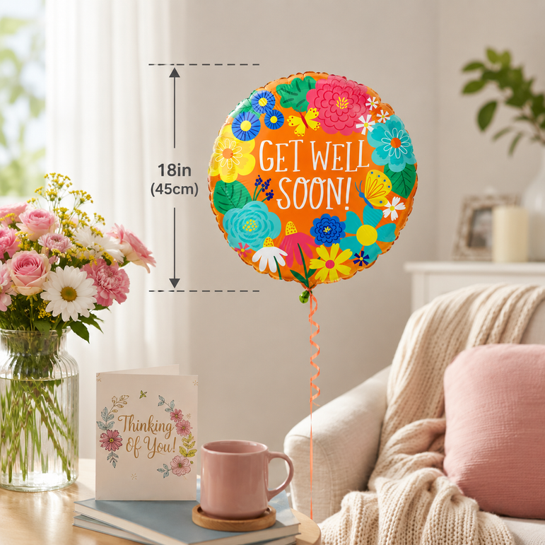 A round 18-inch 'Get Well Soon!' balloon with a colorful floral pattern is shown in a cozy living room setting next to a pink mug, a card, and a vase of flowers. A dimension overlay indicates the balloon's height and diameter.
