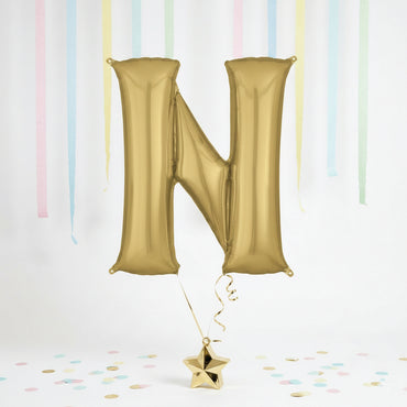 Gold letter 'N' balloon with a star-shaped confetti on a light background