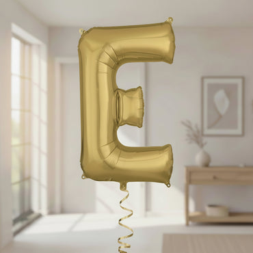 Gold letter 'E' balloon in a room with a blurred background