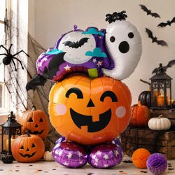 Halloween balloon bouquet featuring a large orange jack-o'-lantern balloon with a black face, a white ghost balloon, a purple witch hat balloon with black bats, and two purple star-patterned round balloons at the base, styled with pumpkins, lanterns, and black bat decals in a room setting.